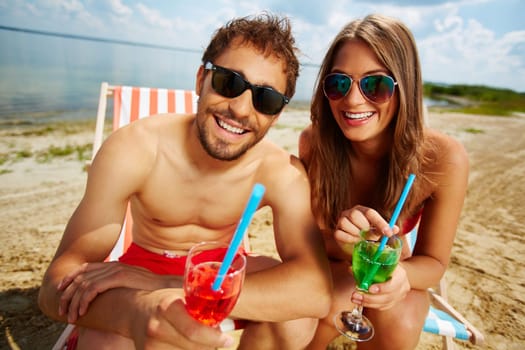 Happy couple with cocktails having party on the seashore