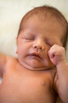 Close-up of a newborn baby lying on a fluffy white blanket