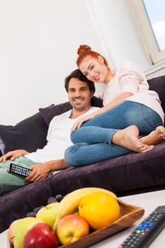 Young couple sits on the couch in the living room and looks away from home