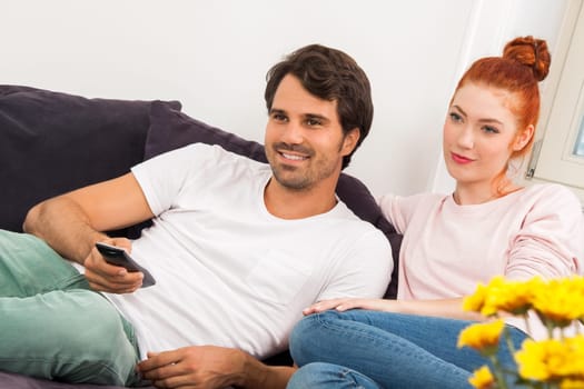 Young couple sits on the couch in the living room and looks away from home