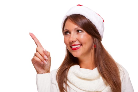 Young attractive woman with red Christmas hat points her finger in one direction isolated on white background