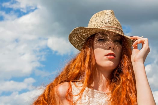 Attractive young woman with long root hair and straw hat outdoors in spring summer in blue sky