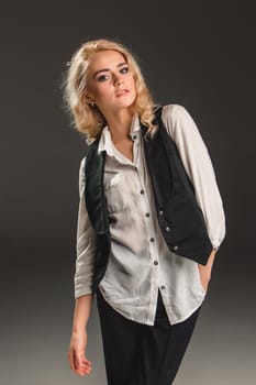 Beauty blond woman  in a black suit and white shirt on a gray background