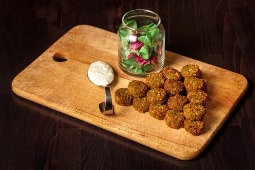 fresh vegetarian falafel  with sauce and fresh herbs on wooden blackboard