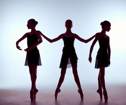 Composition from silhouettes of three young dancers in ballet poses on a gray background.  The outline shooting - silhouettes of girls.