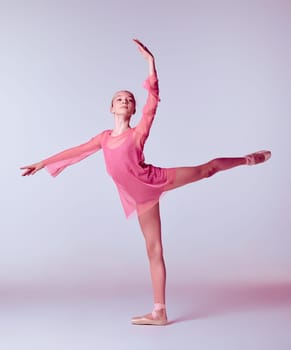 Young ballerina dancer in pink dress showing her techniques on lilac background