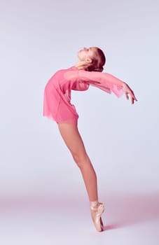 Young ballerina dancer in pink dress showing her techniques on lilac background
