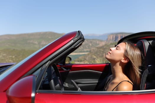 Profile of a convertible car driver breaths fresh air