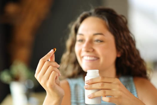 Happy woman ready to eat a vitamin pill at home or restaurant