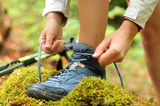 Close up of a hiker hands tying trekking boot laces in the mountain