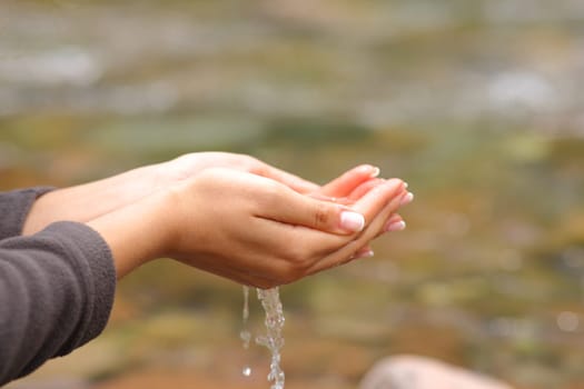 Close up of a woman hands catching fresh raw water from river