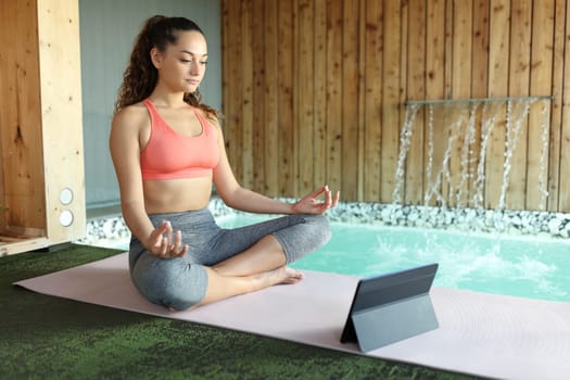 Woman e-learning yoga watching online class in spa pool