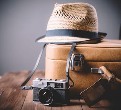 Vintage case, hipster hat, and retro camera on wooden background still life. Summer holiday vacation and adventure traveling concept with copyspace.