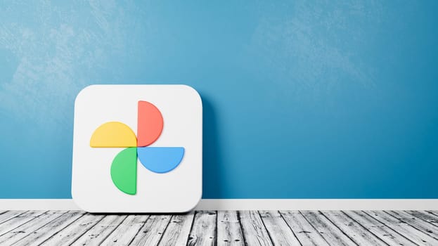 Google Photos App Icon 3D Symbol Shape on Wooden Floor Against Blue Wall with Copy Space 3D Render Illustration