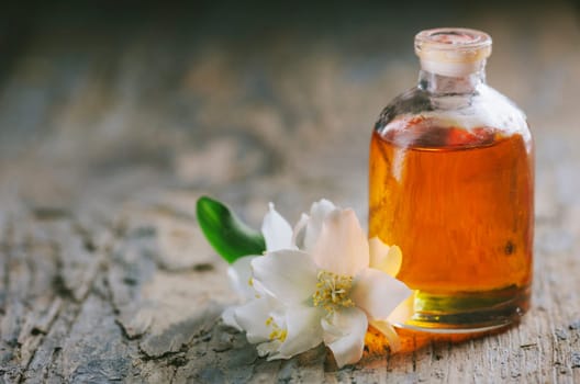 Essential oil with jasmine flower. Aromatherapy massage oil on rustic wooden background.