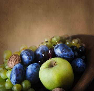 Seasonal thanksgiving fruit in wooden bowl. Vintage still life with autumn farm crops over art canvas background.