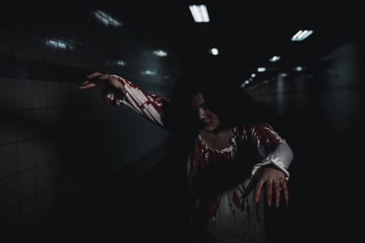 Bloody halloween makeup. Horror bloodthirsty ghost girl hair covering face and eye reach arm out, Asian woman zombie with blood she death and scary at night in tunnel, Happy halloween day concept