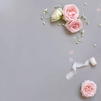 Pink and cream roses and silk ribbons on grey top view. Romantic flat lay with pastel flowers. Wedding, Valentines, Spring or Mothers day concept