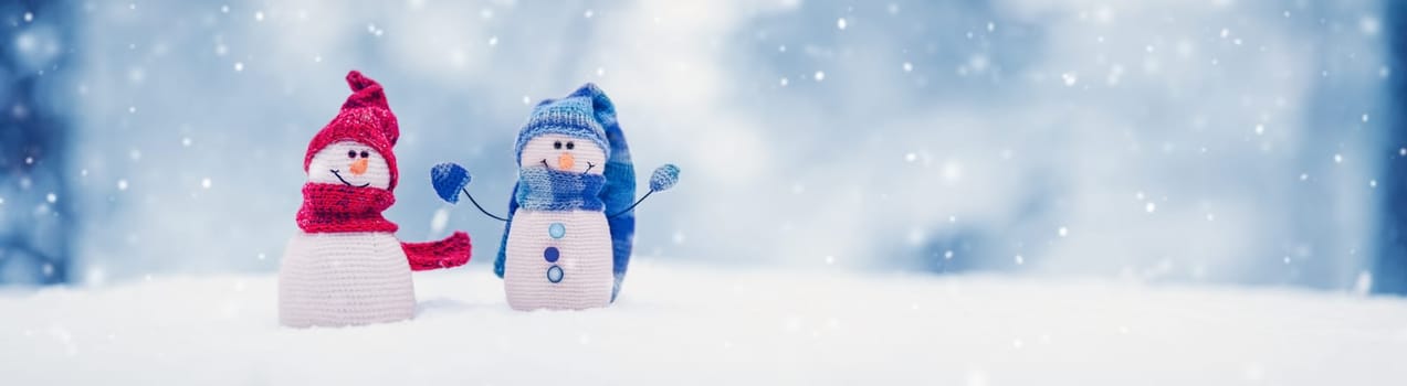 Little knitted snowmen on the white snow on blue background. Beautiful panoramic view.
