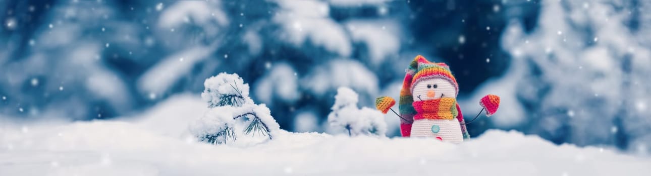 Little knitted snowman on the white snow on blue background. Beautiful panoramic view.