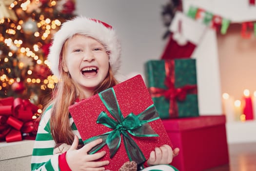 Little girl sitting in the Christmas decorating room. Concept of the christmastime and New Year eve.