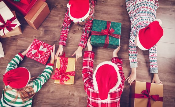 Group of children lying on the floor indoors with Christmas gifts. Concept of Christmastime and New Year eve.