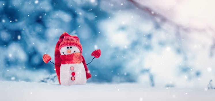Little knitted snowman on the white snow on blue background. Beautiful panoramic view.