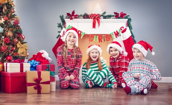 Group of children sitting on the floor indoors on Christmas morning. Concept of the holiday eve and New Year.