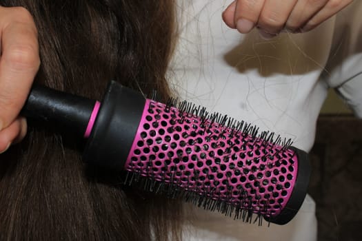 A girl with long dark hair removes her hair from a comb. Hair loss problem.