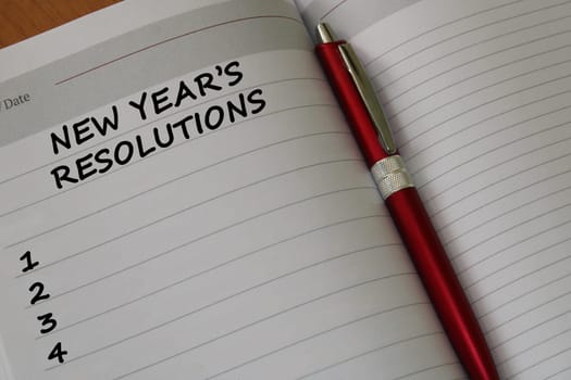 Notepad with a pen on a wooden table. View from above. The concept of resolutions for the new year.