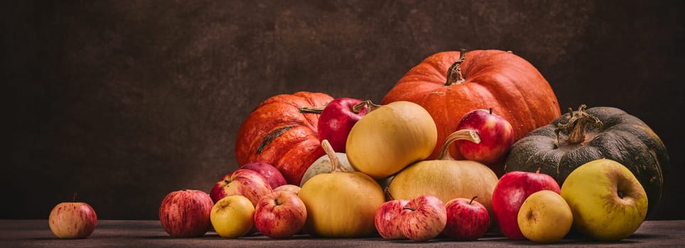 Thanksgiving background. Festive still life with pumpkins and apples on dark brown background with copy space. Happy Thanksgiving  day, autumn harvest or Halloween.