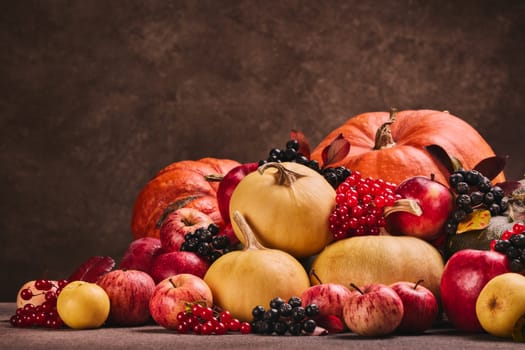 Thanksgiving background. Festive still life with pumpkins, berries, autumn leaves and apples on dark brown background with copy space. Happy Thanksgiving  day, autumn harvest, Halloween.