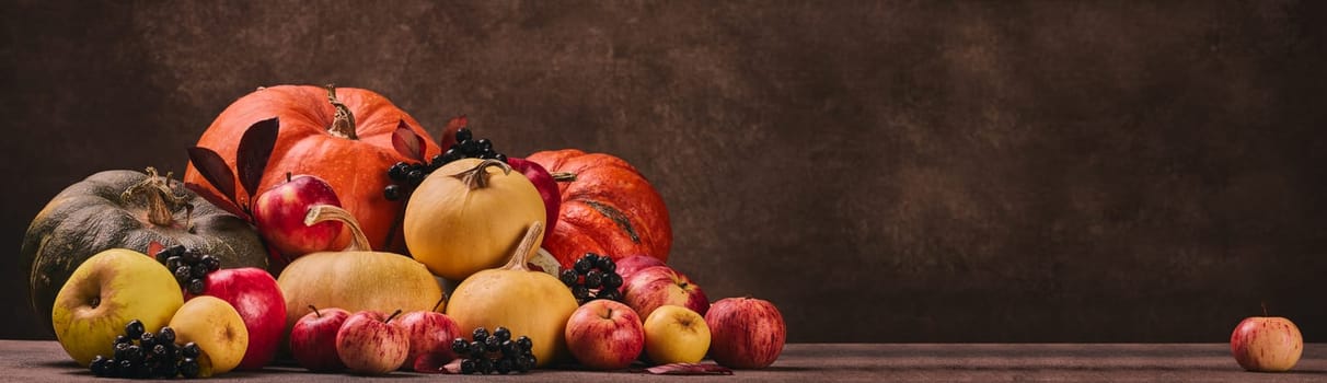 Thanksgiving background. Festive still life with pumpkins, berries, autumn leaves and apples on dark brown background with copy space. Happy Thanksgiving  day, autumn harvest, Halloween.