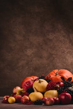 Thanksgiving background. Festive still life with pumpkins, berries, autumn leaves and apples on dark brown background with copy space. Happy Thanksgiving  day, autumn harvest, Halloween.
