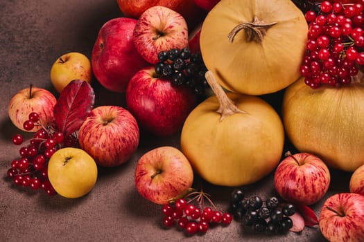 Thanksgiving background. Festive still life with pumpkins, berries, autumn leaves and apples on dark brown background. Happy Thanksgiving  day, autumn harvest, Halloween. Top view