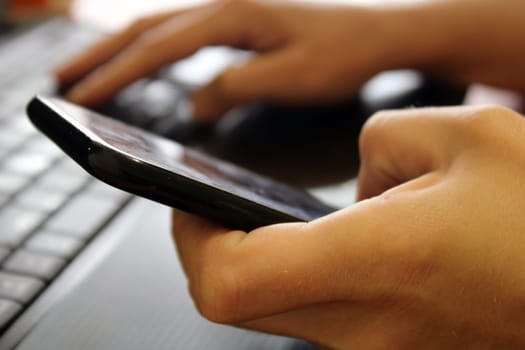The girl sits at a laptop and holds a smartphone in her hands. Business concept. Online Shopping