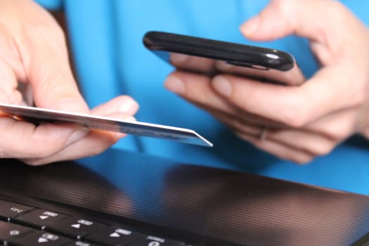 The girl sits at a laptop and holds a smartphone in her hands. Business concept. Online Shopping