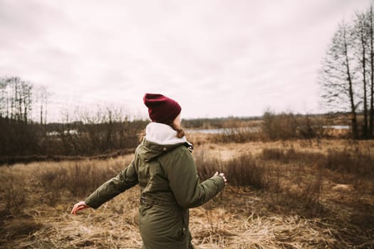 Single Young Pretty Caucasian Happy Girl Woman In Green Jacket Running In Autumn Forest. Enjoy Outdoor Fall Nature.