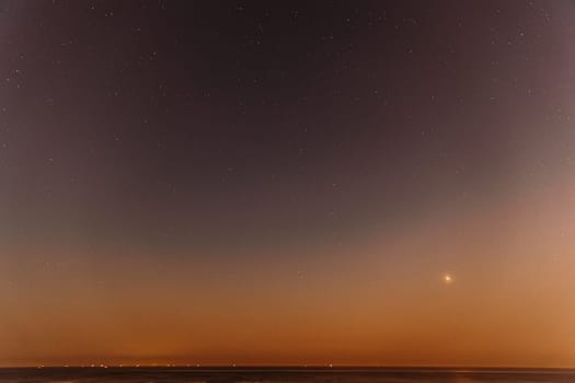 Real Colorful Night Sunset Sky Stars. Natural Starry Sky Above Sea Seascape Ocean Beach. Background.