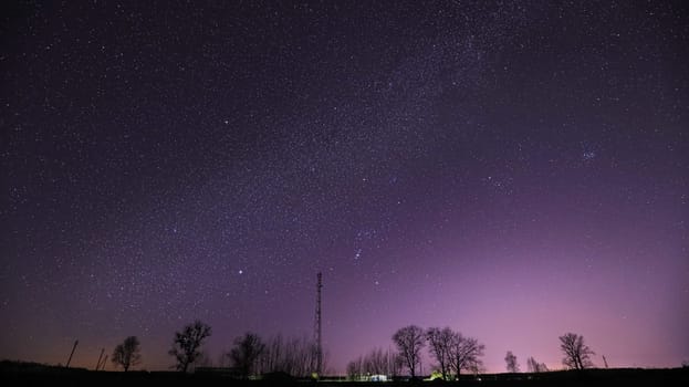 Real Night Sky Stars Above Landscape With Telecommunications Cell Phone Tower Or  With Antenna. Natural Starry Sky With Milky Way Galaxy Above Rural Countryside Landscape In Belarus.