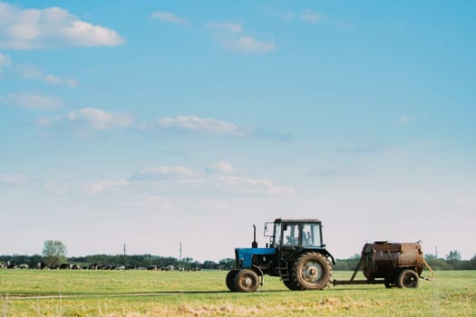 Old Tractor With Tank Rides On Countryside Road. Beginning Of Agricultural Spring Season.