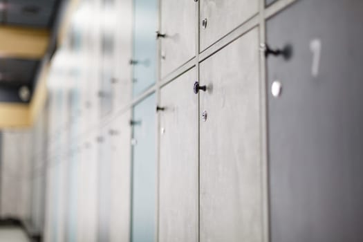 Lockers alley. Close-up of closet for temporary storage of things in public place. Focus on handle of gray door under which key lock is located. Storage of things in gym.