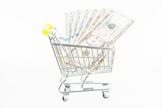 Miniature shopping cart with US dollars isolated over white background