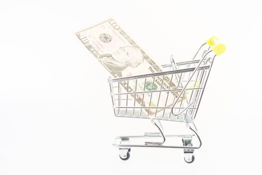 Miniature shopping cart with US dollars isolated over white background