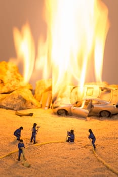 Miniature firefighters at a car accident scene in flames