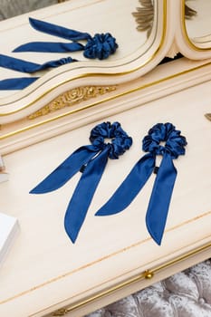 Hair ties made of silk fabric for real elegant ladies. Exquisite women's handmade blue scrunchy lie on table among luxury interior details. Hair accessories concept.