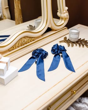 Hair ties made of silk fabric for real elegant ladies. Exquisite women's handmade blue scrunchy lie on table among luxury interior details. Hair accessories concept.
