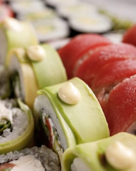 Close-up view of various sushi rolls with different fillings on black metal slate. Sushi set with salmon, red caviar, cheese, cucumber, avocado and sesame seeds. Sushi background.