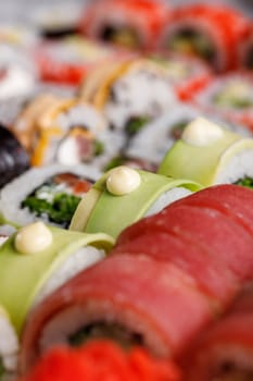 Oriental traditional seafood. Close up of original sushi rolls with different fillings standing and lying close to each other. Macro view of sushi set with different ingredients inside.
