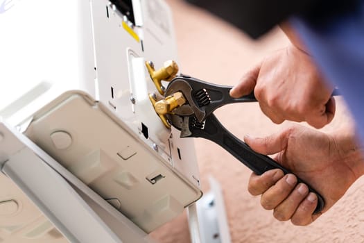 Tools and instruments. Male repairman works using two adjustable wrenches at once. Close up of connecting parts when installing air conditioner. DIY concept.